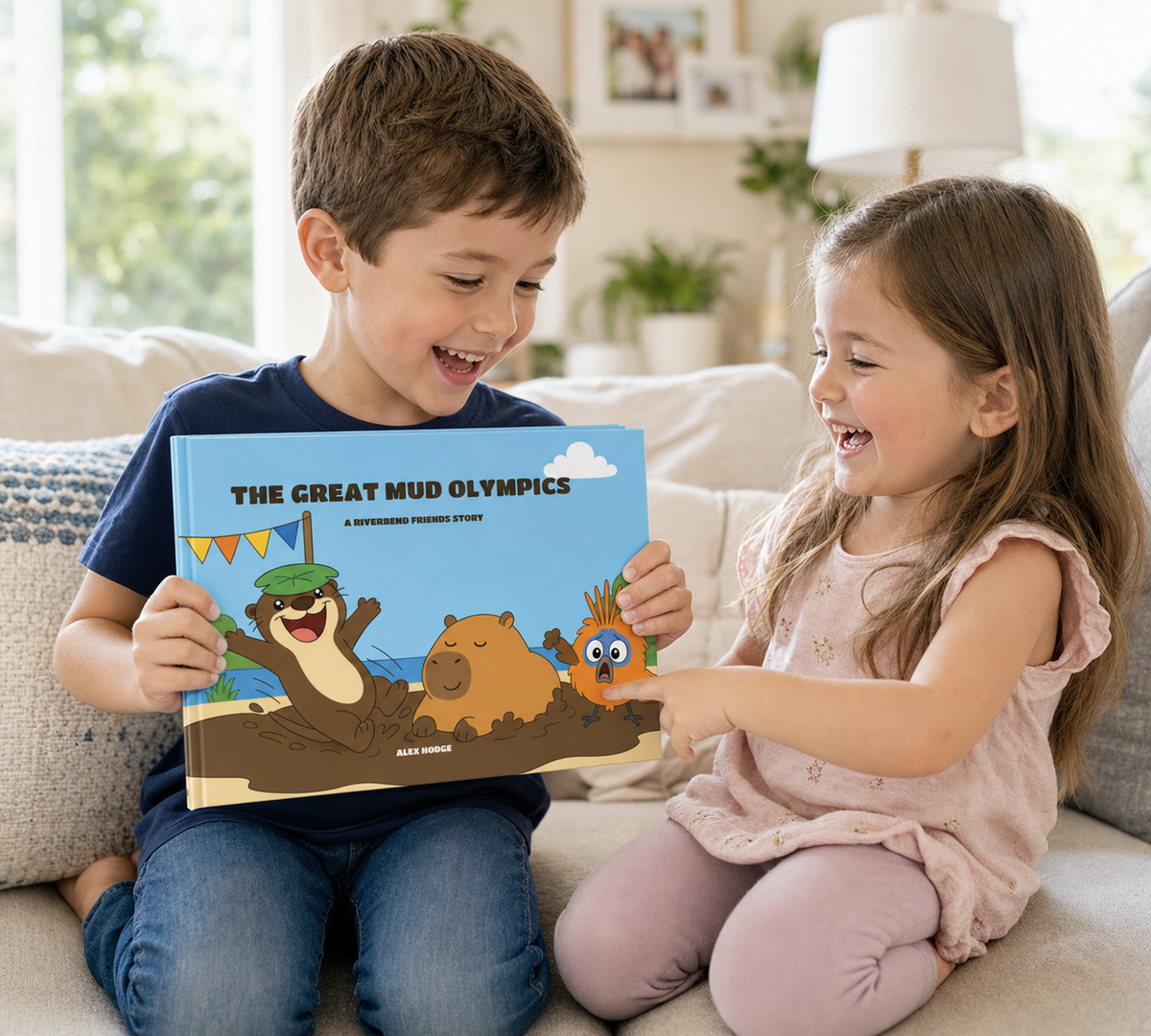 Brother and sister giggling over The Great Mud Olympics hardcover on the sofa